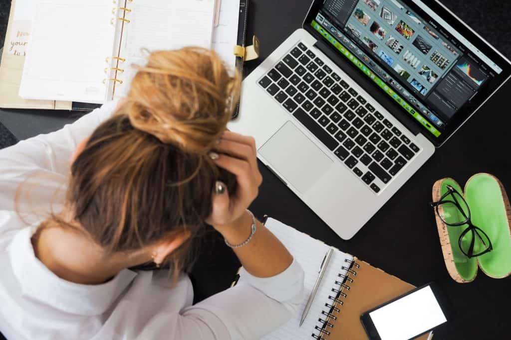 women at desk with head in hands